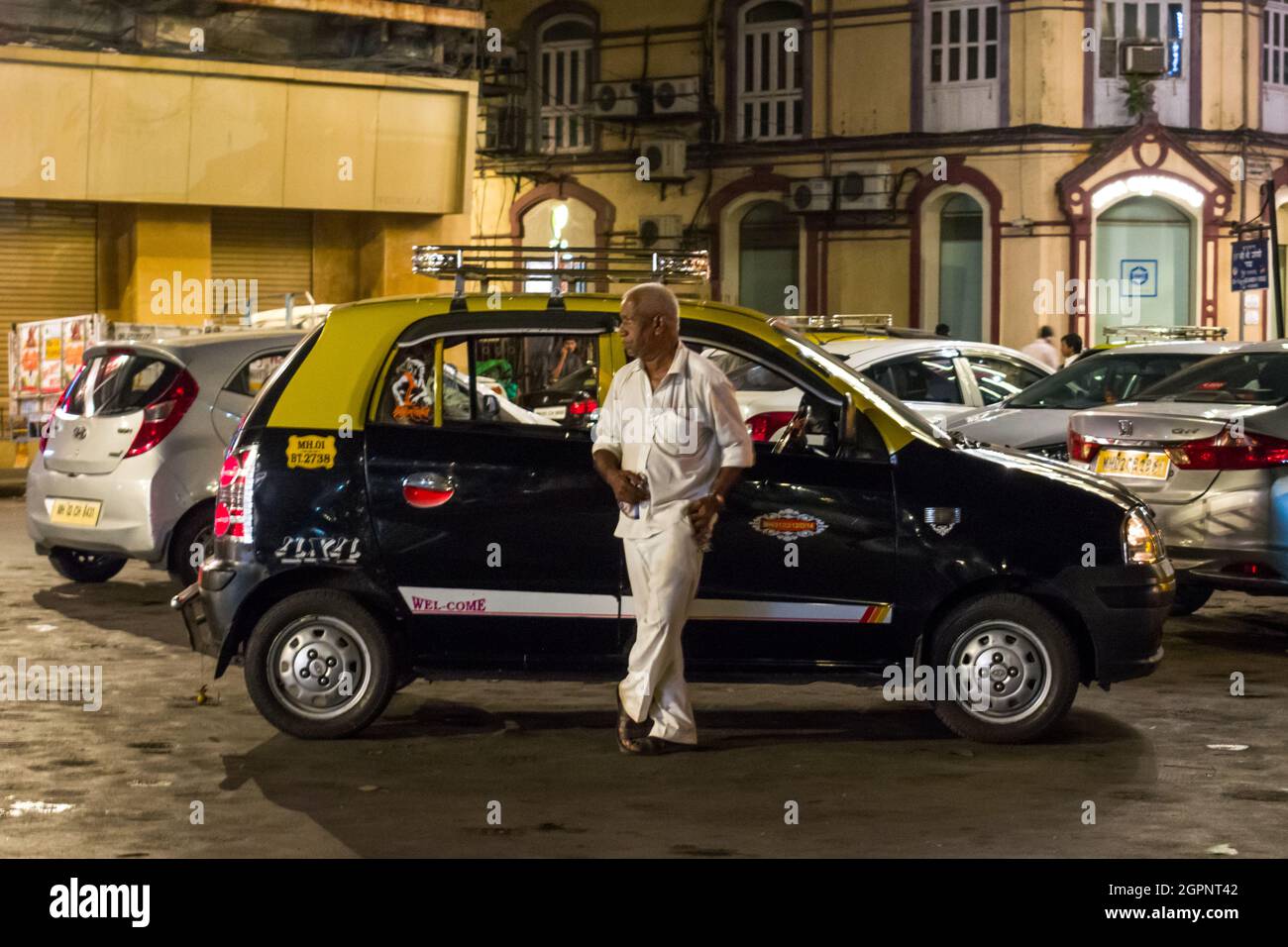 A candid shot of a taxi driver waiting for a customer in front of his cab in South Mumbai, India. Stock Photo