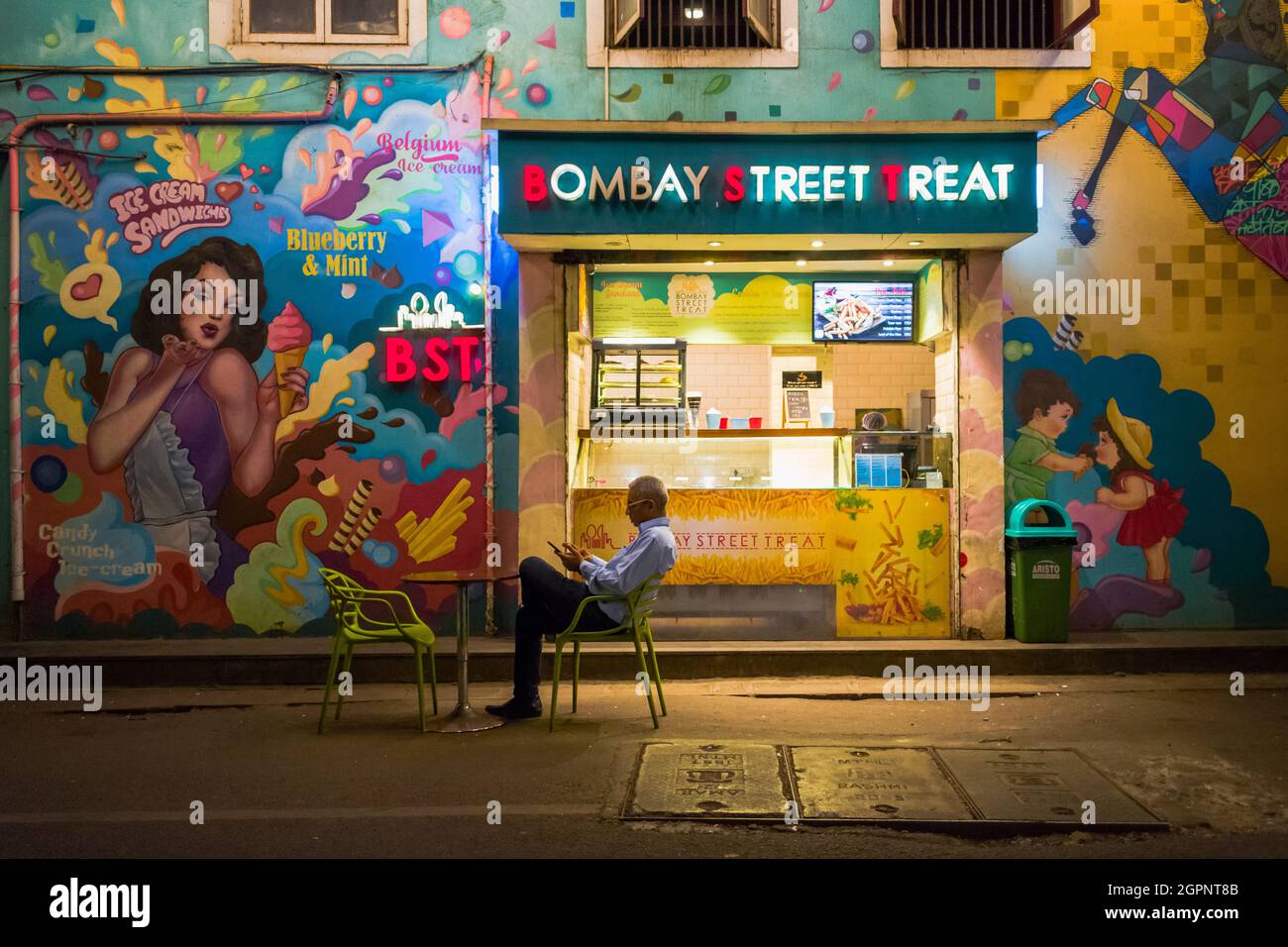 A candid shot of a man sitting outside a cozy cafe in South Mumbai, India. Architecture and landmark of Mumbai. Stock Photo