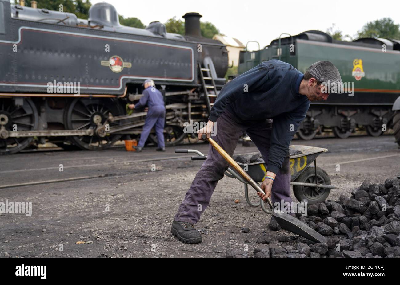A volunteer shovels coal into a wheel barrow at Ropley yard on the Mid