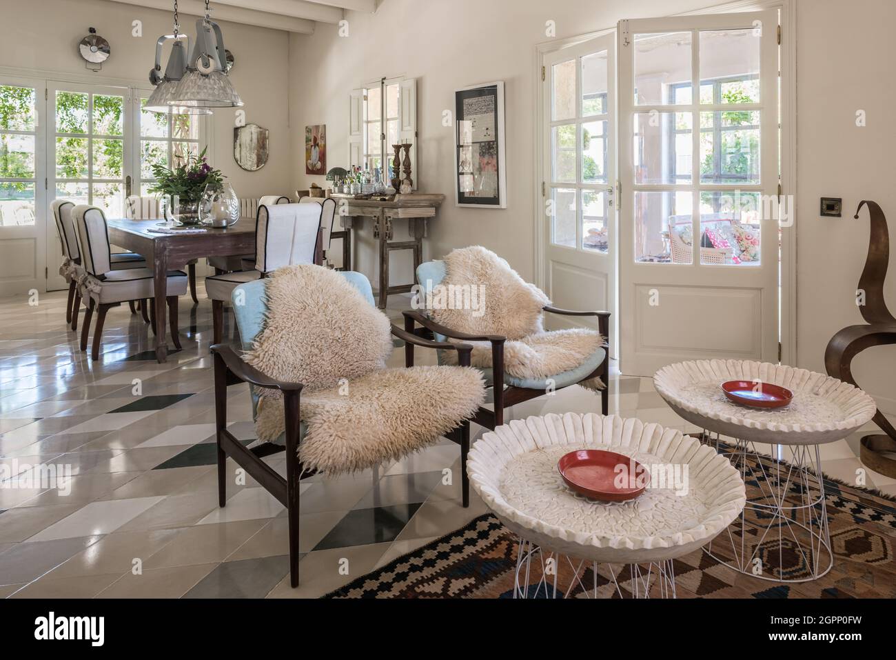 Pair of chairs with sheepskin throws in open plan Spanish villa
