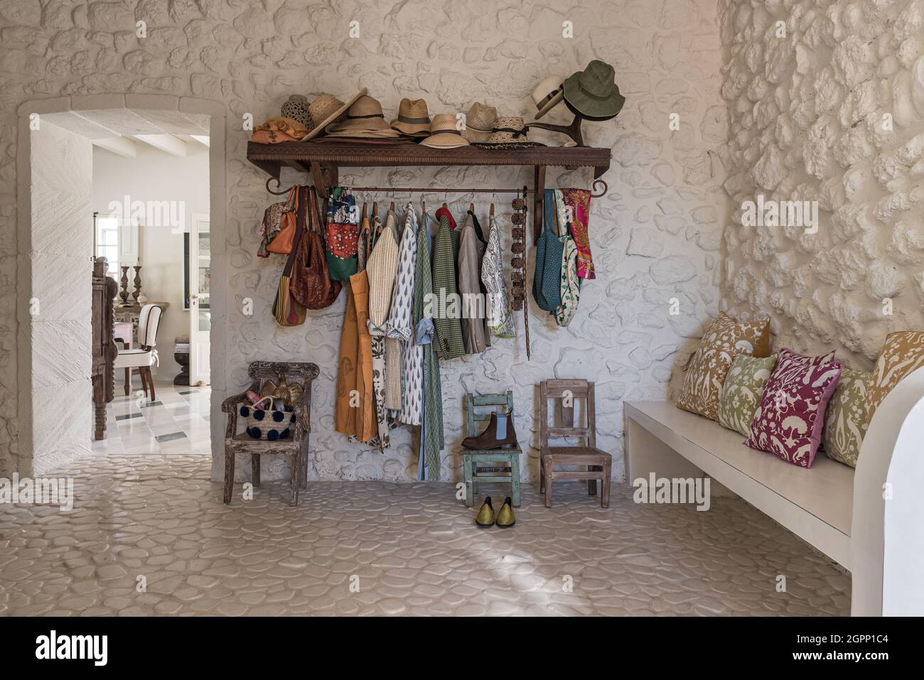 Sunhats and coats in cloakroom with river stones set in cement, Spanish