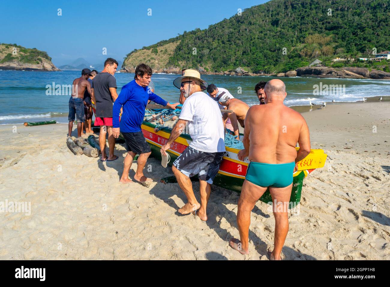 People from the community and other participants preparing to push a new artisanal fishing canoe into the sea. The inauguration of a canoe is a tradit Stock Photo
