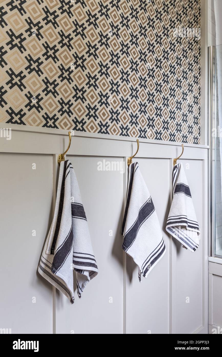 Hicksonian wallpaper with three hand towels on hooks in Sussex bathroom, UK Stock Photo