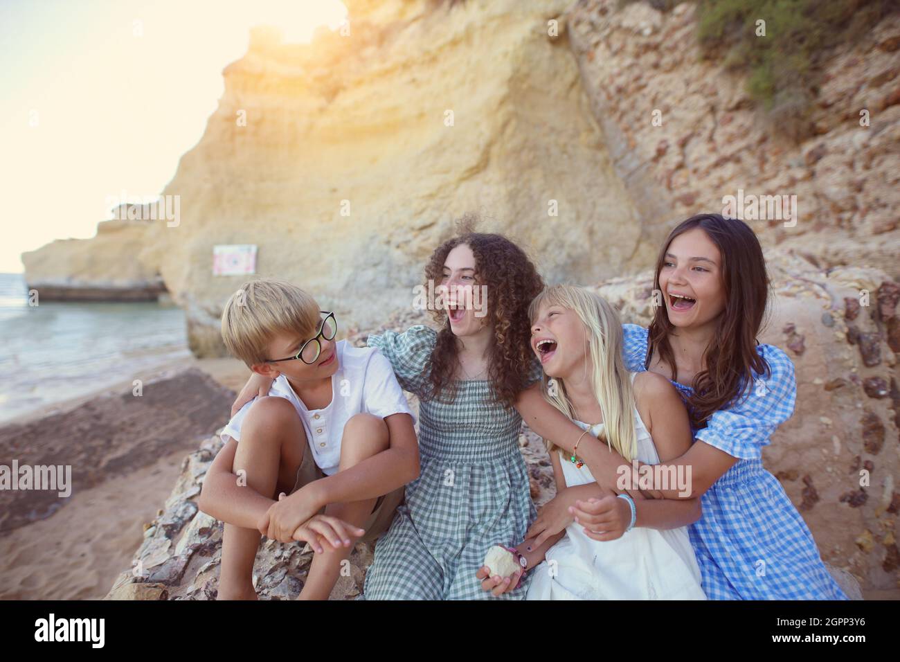 young friends are laughing on the beach by the cliffs Stock Photo