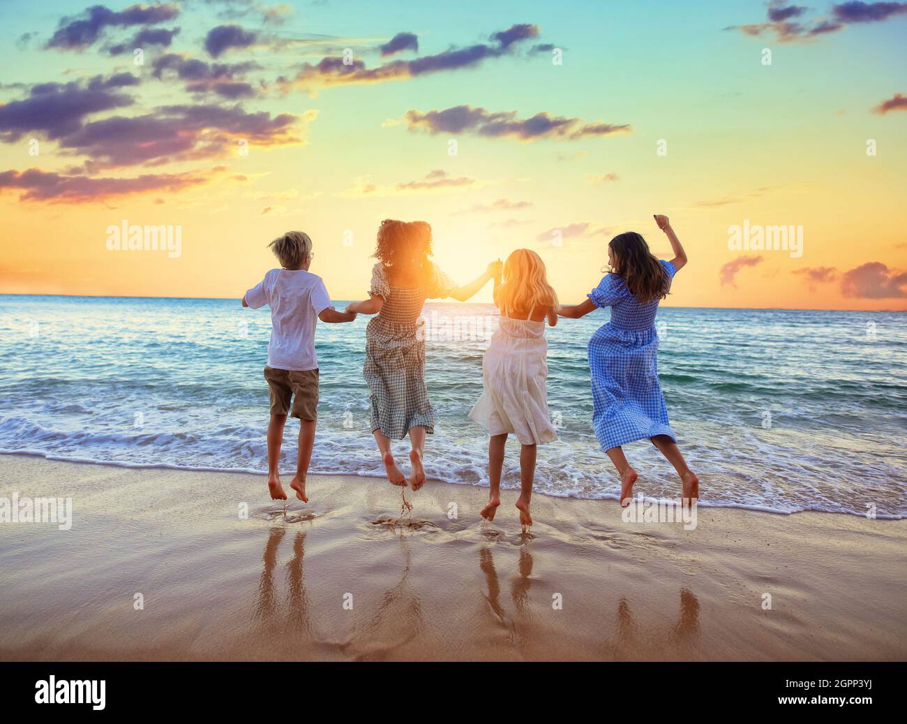 young kids are jumping on the shore of the ocean Stock Photo