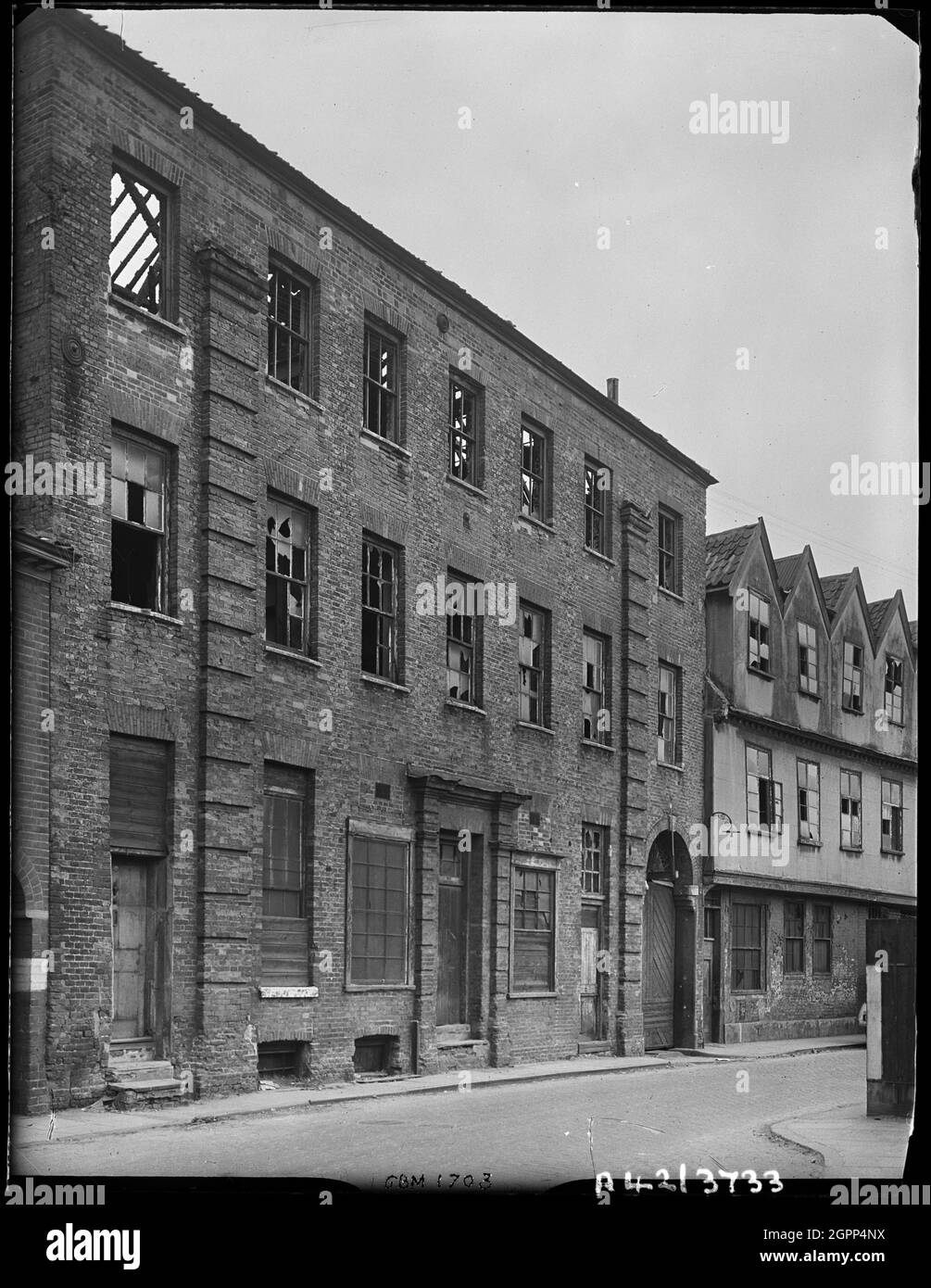Norfolk Iron Works, Coslany Street, Norwich, Norfolk, 1942. The front elevation of 24 Coslany Street showing bomb damage, with number 22 visible in the background. Numbers 22 and 24 Coslany Street formed part of the Norfolk Iron Works, premises of Barnard's Limited who were wire netting manufacturers. Modern housing now occupies the site. Stock Photo