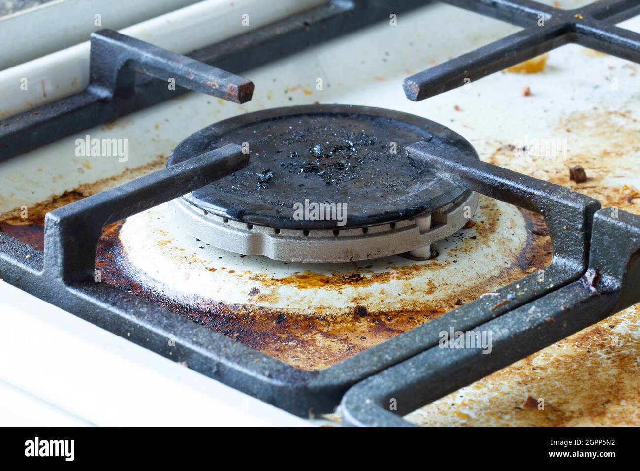 Dirty gas stove surface. Large gas burner and cast iron grate of a gas oven surrounded by old leftovers of food and drinks. Top area surface and burn Stock Photo