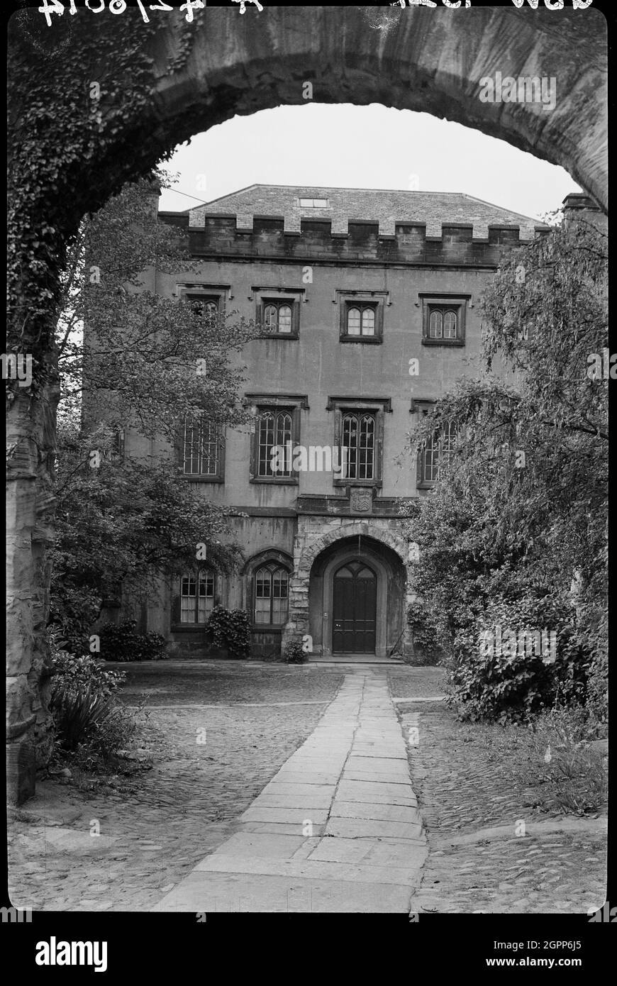 Wall with Archway in front of No. 9, The College, County Durham, 1942. An exterior view of St Mary's College, now known as the Chorister School, seen from the north through an archway. The former prebendal house, now a school, has medieval fabric with alterations made in the 17th and 18th centuries. The main house has three storeys and five windows with towers at each corner. The parapet is embattled. At the rear of the building is the short arm of the L-shaped plan. The arch in the foreground is part of a garden wall with medieval, 17th and 18th century material. The wall may have formerly be Stock Photo