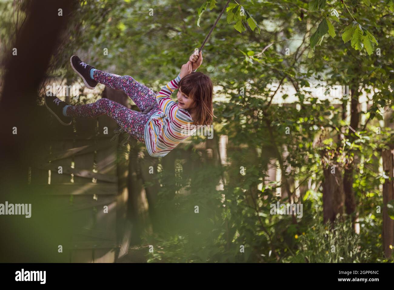 Happy girl on a tree swing in the garden Stock Photo - Alamy
