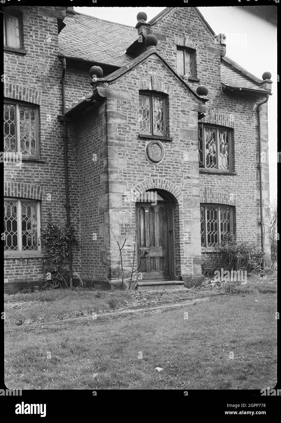 Knobb Hall, Manchester, 1942. An exterior view of Knobb Hall, showing the porch in the front facade. The hall was built in the c17th century, and was demolished post 1942. The front facade has three bays and two storeys, with attics in the two end gables. The porch was two storeys and projecting, with a gabled roof. The gables throughout the hall has ball finials on each corner. Stock Photo