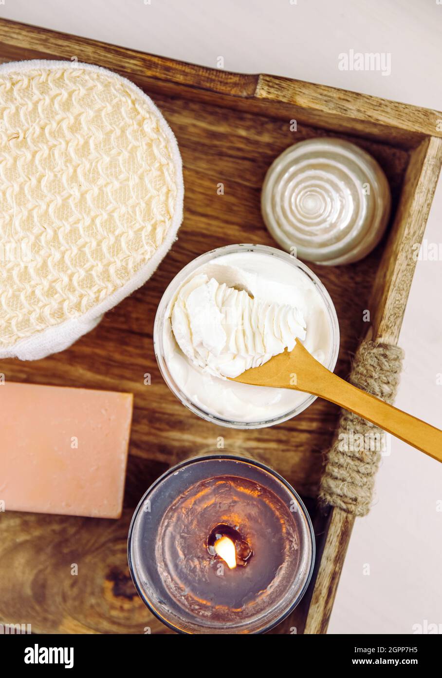 Bodywhip also known as body butter, skin care moisturizer cream on wood spoon and jar on natural wooden tray with bath sponge and candle. Stock Photo