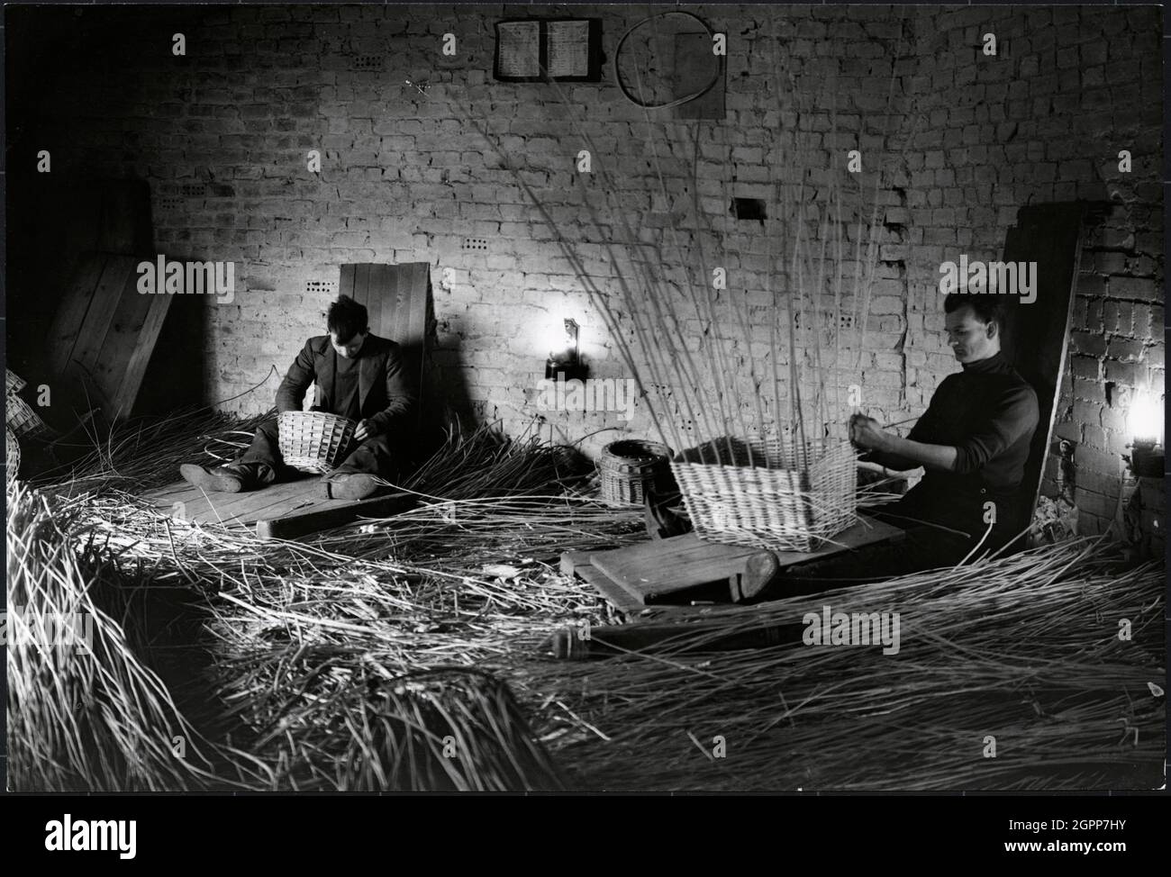 Basket makers, King's Sedge Moor, High Ham, South Somerset, Somerset, 1930s. Basket weavers at work in a small factory on King's Sedge Moor. The caption on the reverse of the print states: &quot;Basket workers working with only small oil lamps to keep the room at an even temperature&quot;. Stock Photo