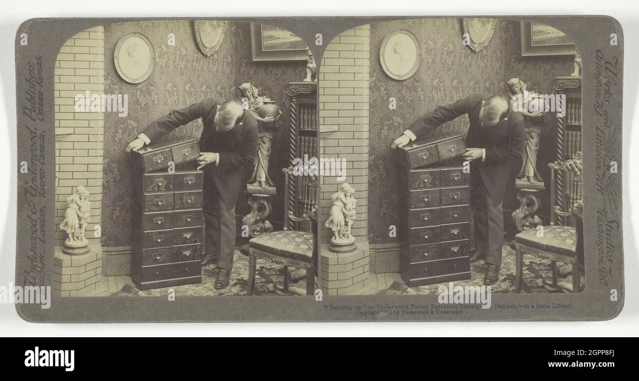 Building up an Underwood Patent Extension Stereograph Cabinet, - in a home Library, 1901. [Piece of furniture designed to house a stereoscope - equipment for viewing stereographic photographs]. Albumen print, stereocard. Stock Photo