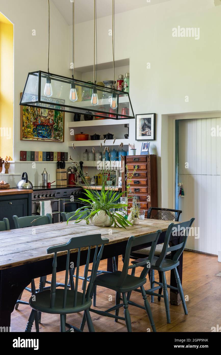 Pendant light above kitchen table with mismatched chairs in former 19th