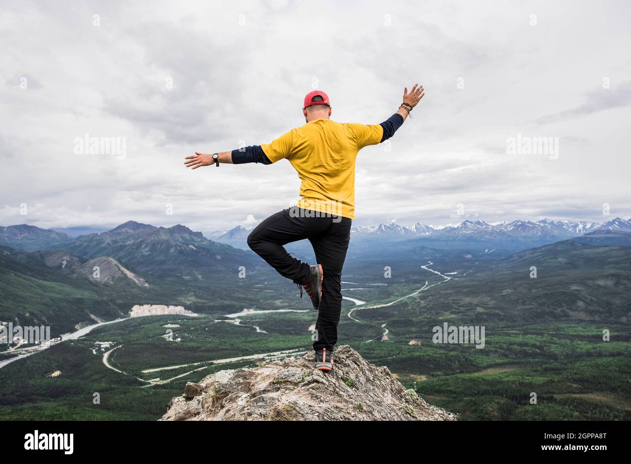 USA, Alaska, Hiker standing on one leg on mountain top in Denali National Park Stock Photo