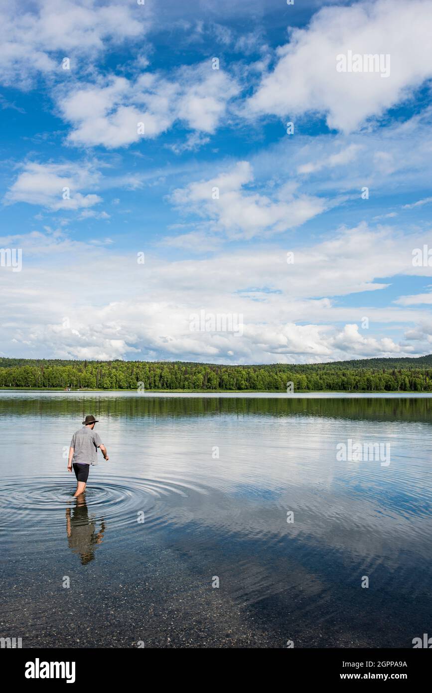 USA, Alaska, Rear view of man wading in water in Kenai Fjords National Park Stock Photo