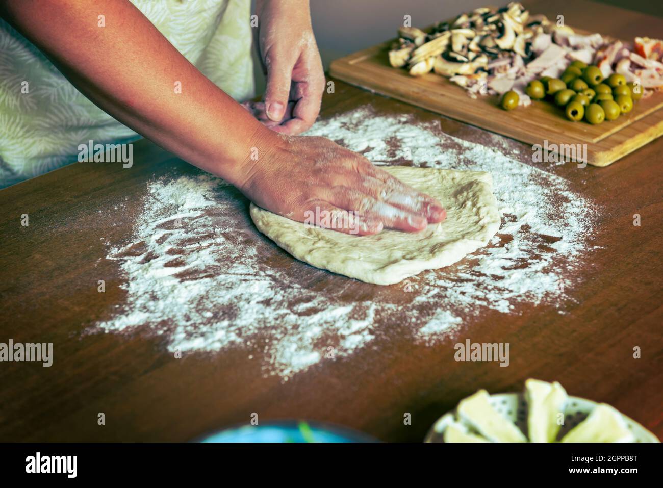 Preparing the Italian pizza. Kneading yeast dough pizza with mushrooms, olives and ham. Stock Photo