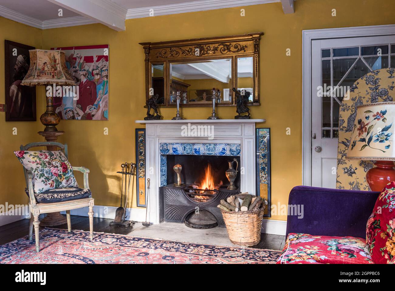 Georgian fire with Delft tiles and contrasting fabrics in Suffolk living room. Stock Photo