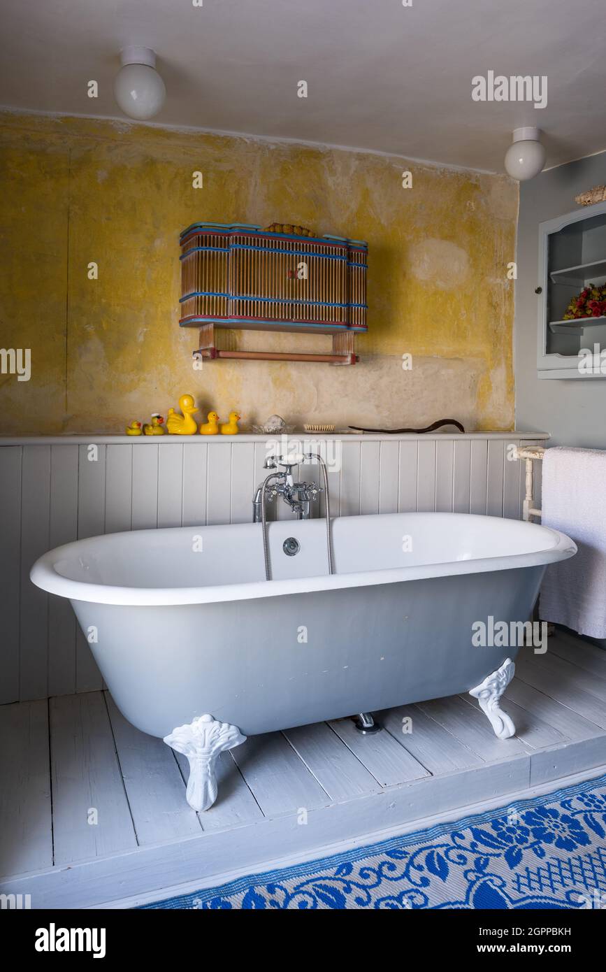 Wall mounted cabinet and rubber ducks with freestanding bath in Suffolk cottage. Stock Photo