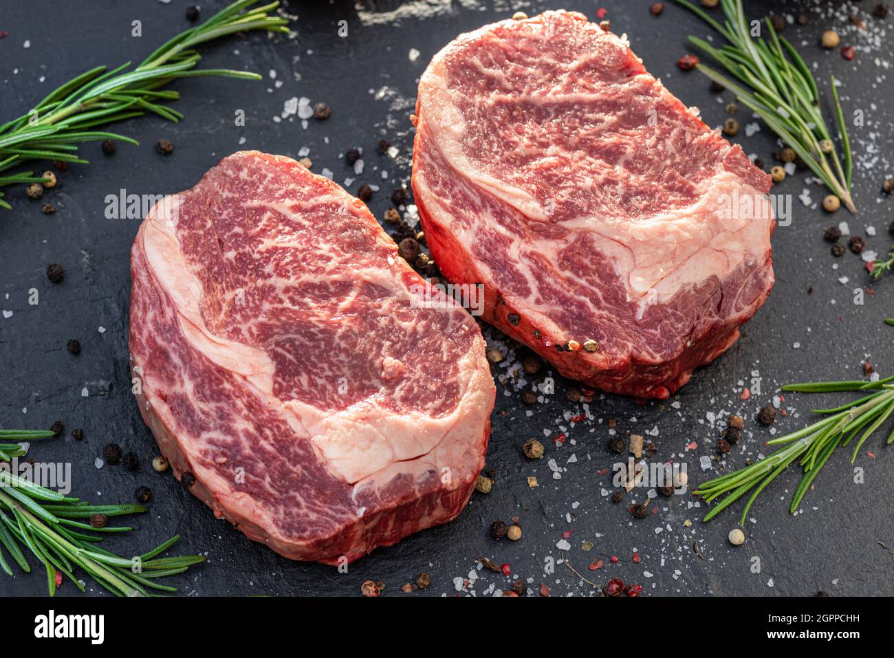 Raw Ribeye steaks with salt and herbs on grey board. Top view Stock ...