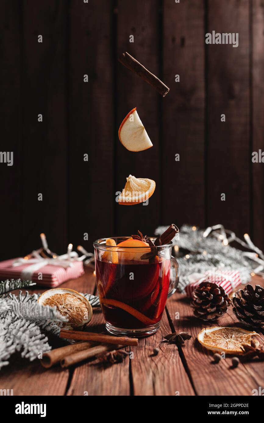 Christmas cup of Mulled Wine on table, levitating cinnamon stick, orange, apple Stock Photo