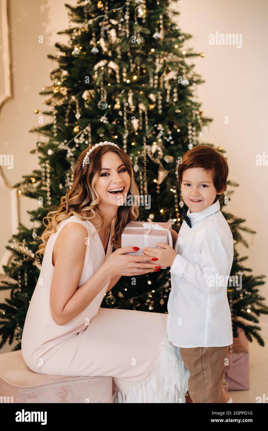 Mother gives Christmas gift to his little son for a New Year. Mom and son  opening Christmas presents Stock Photo - Alamy