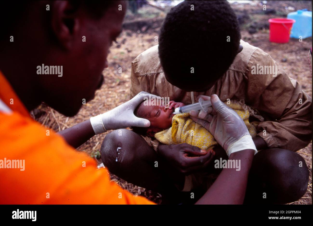 A MSF (Médecins Sans Frontières) doctor feeds a baby with a plastic syringe in a Rwandan refugee camp where multitudes of people fleeing from the genocide and civil war in neighbouring Rwanda wait in a refugee camp in Goma in the Democratic Republic of Congo. Stock Photo
