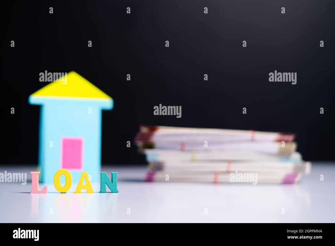 Selective focus on loan , Concept of home loan available showing with money bundle next to home in background. Stock Photo