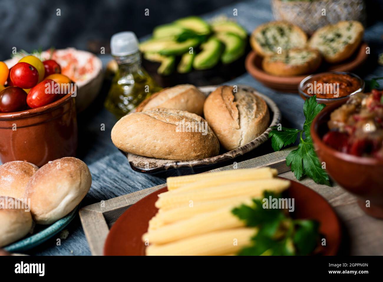 closeup of a table with some different ingredients to prepare vegan sandwiches or appetizers, such as some cooked baby corns, some different bread bun Stock Photo