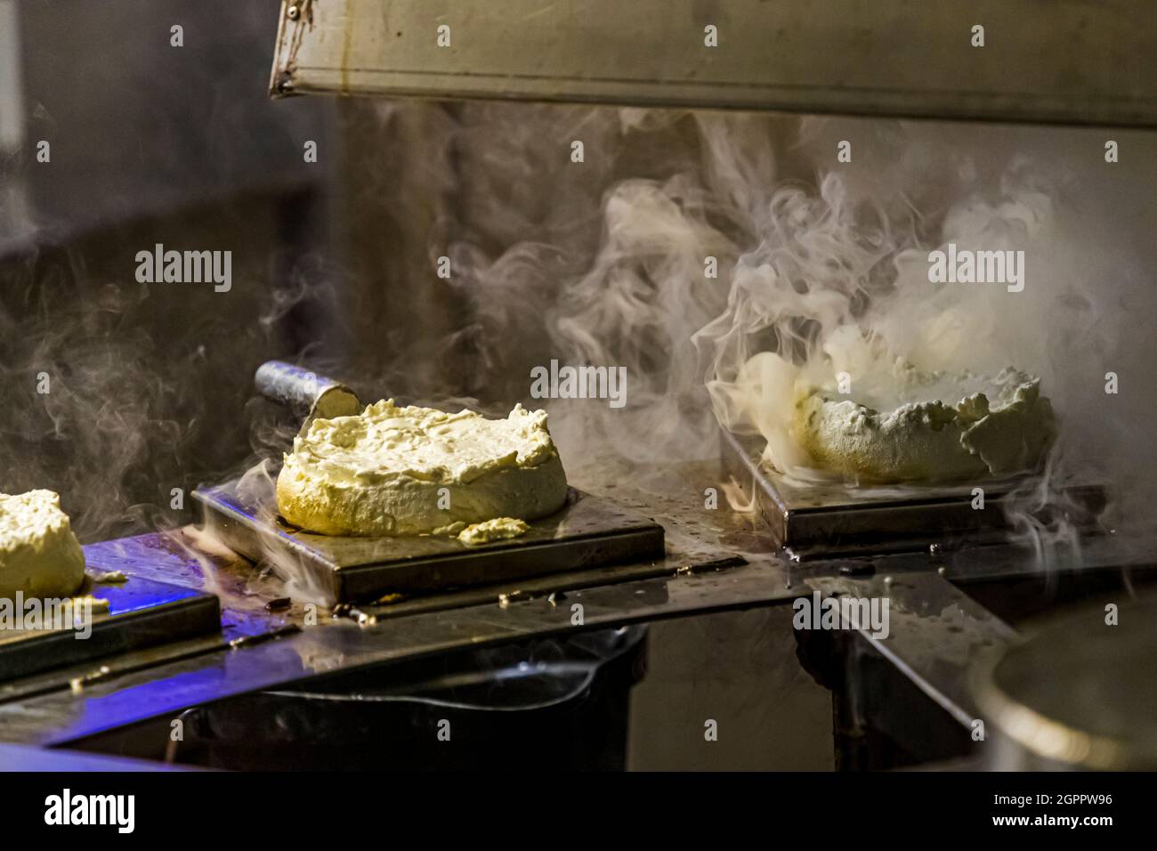 Production of the unique smoked cheese in the Gundestrup Dairy and Brewery (Gundestrup Mejeri og Bryghus). Each fresh cheese is passed through the smoke while lying on a grate for 20 seconds. After that the rygeost has a subtle smoke aroma. Gundestrup, Svendborg, Denmark Stock Photo