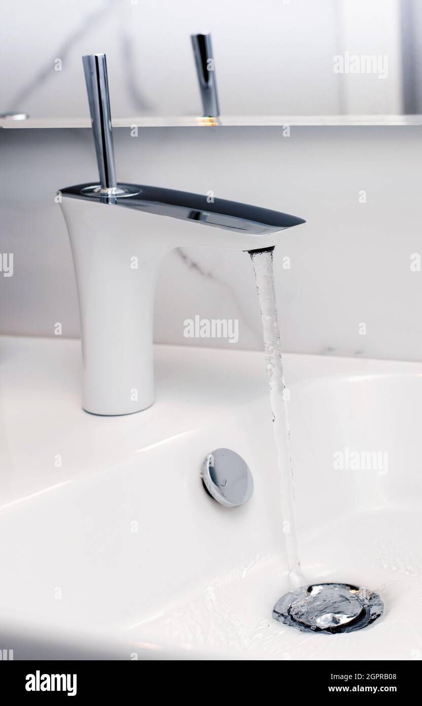 Open tap spilling water into the sink Stock Photo