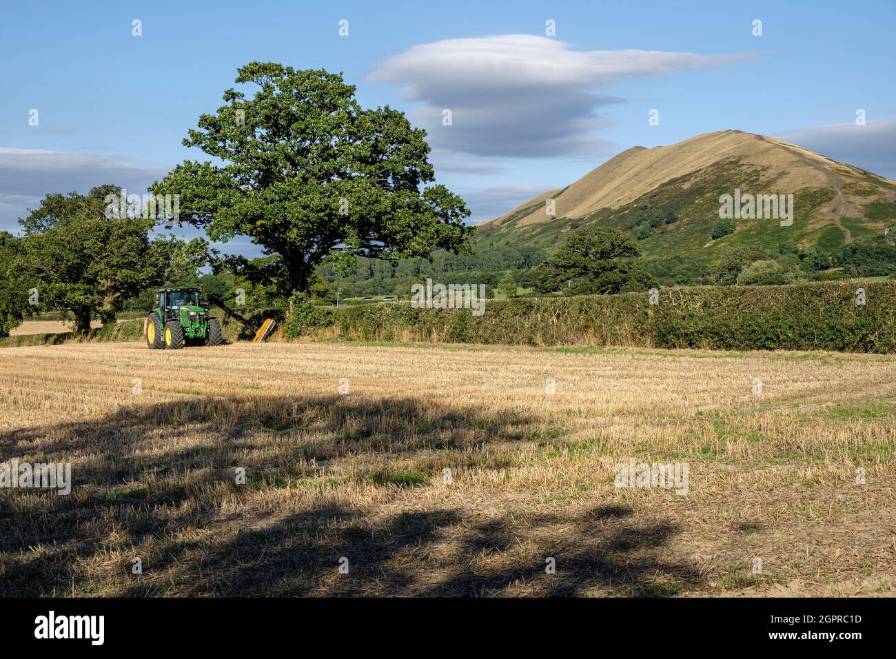 A farmer cutting a field hedge and a view to The Lawley, near All Stretton, Shropshire Stock Photo