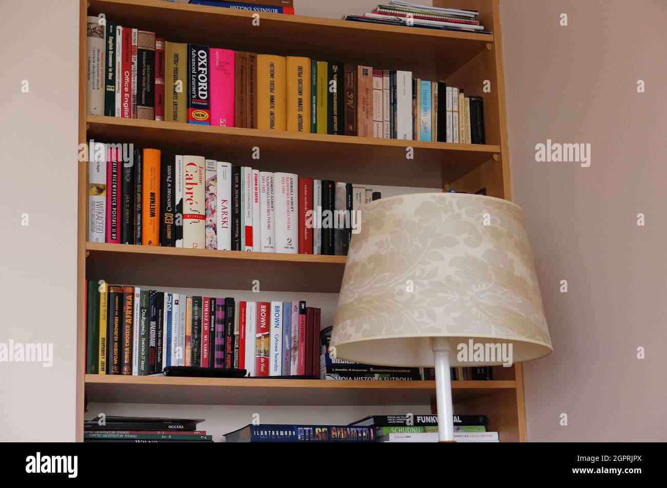 POZNAN, POLAND - Nov 29, 2015: A collection of books on wooden shelves and  a beautiful lamp at home Stock Photo - Alamy