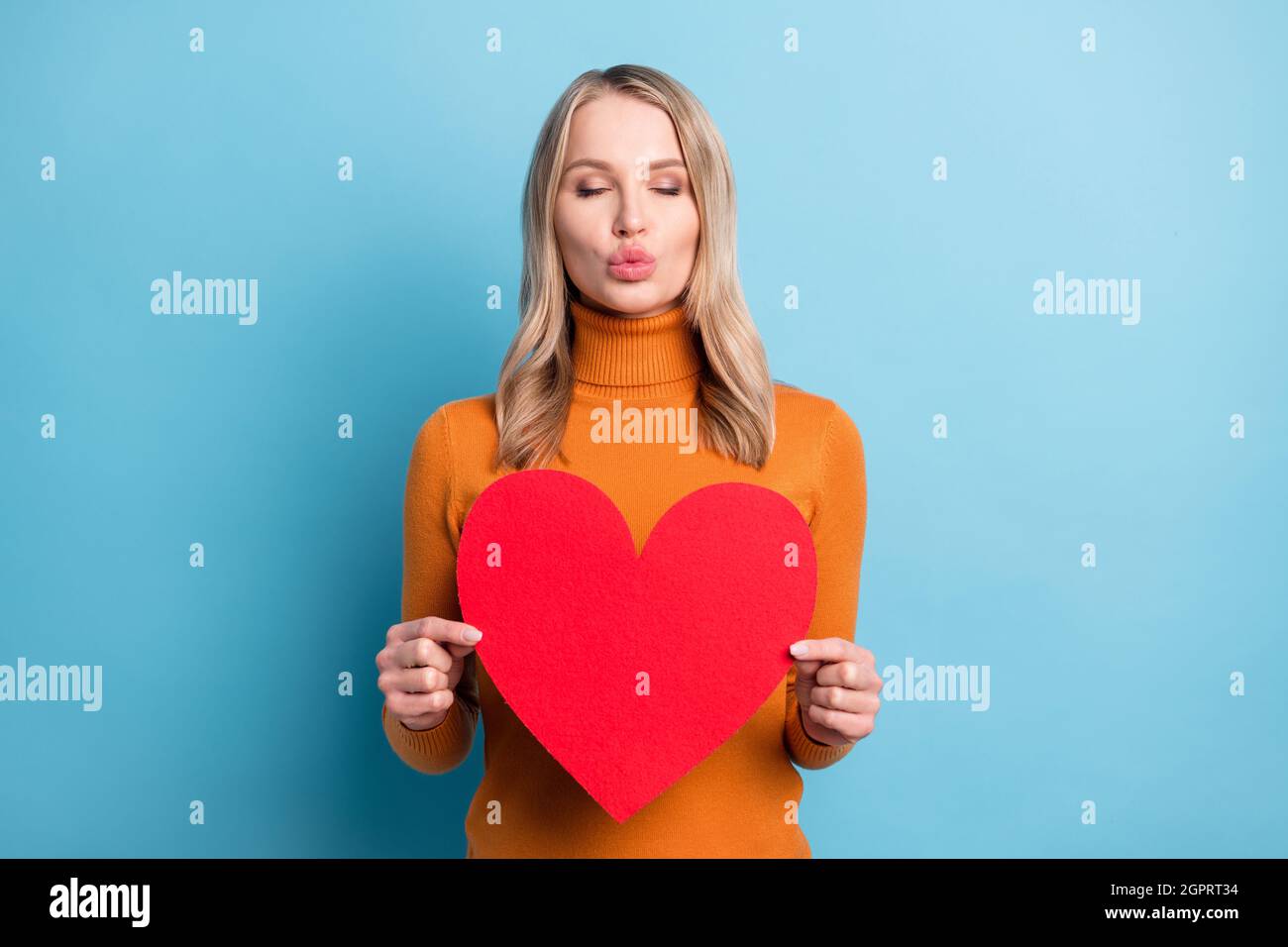 Photo of flirty charming young pretty woman hold hands big red paper ...
