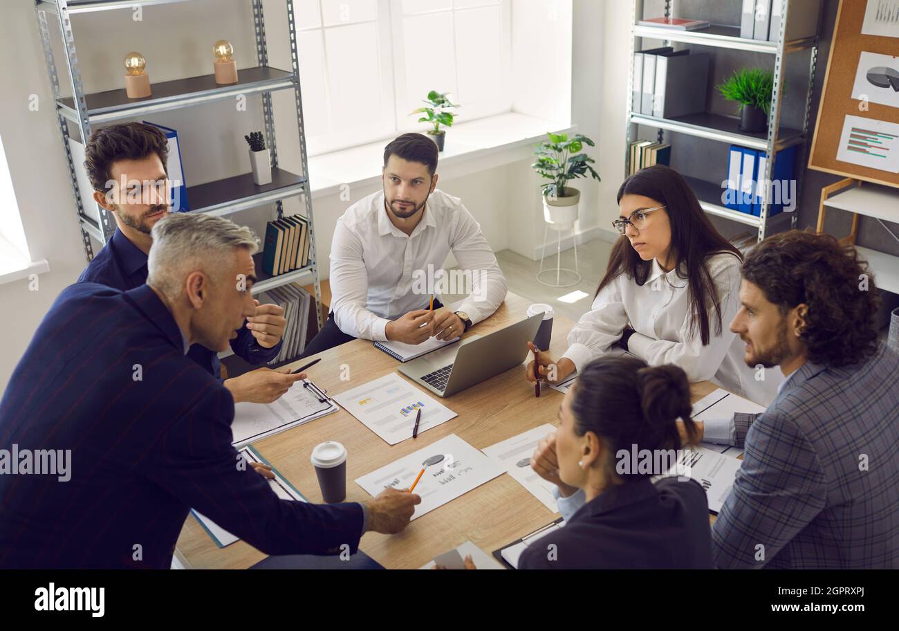 Senior employee makes business development suggestions to his colleagues sitting at the table. Stock Photo