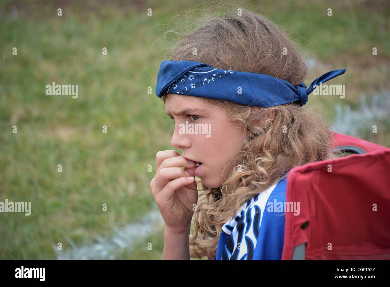 Worried 11 year old soccer player with blue head band and space of text or copy watching her team lose Stock Photo