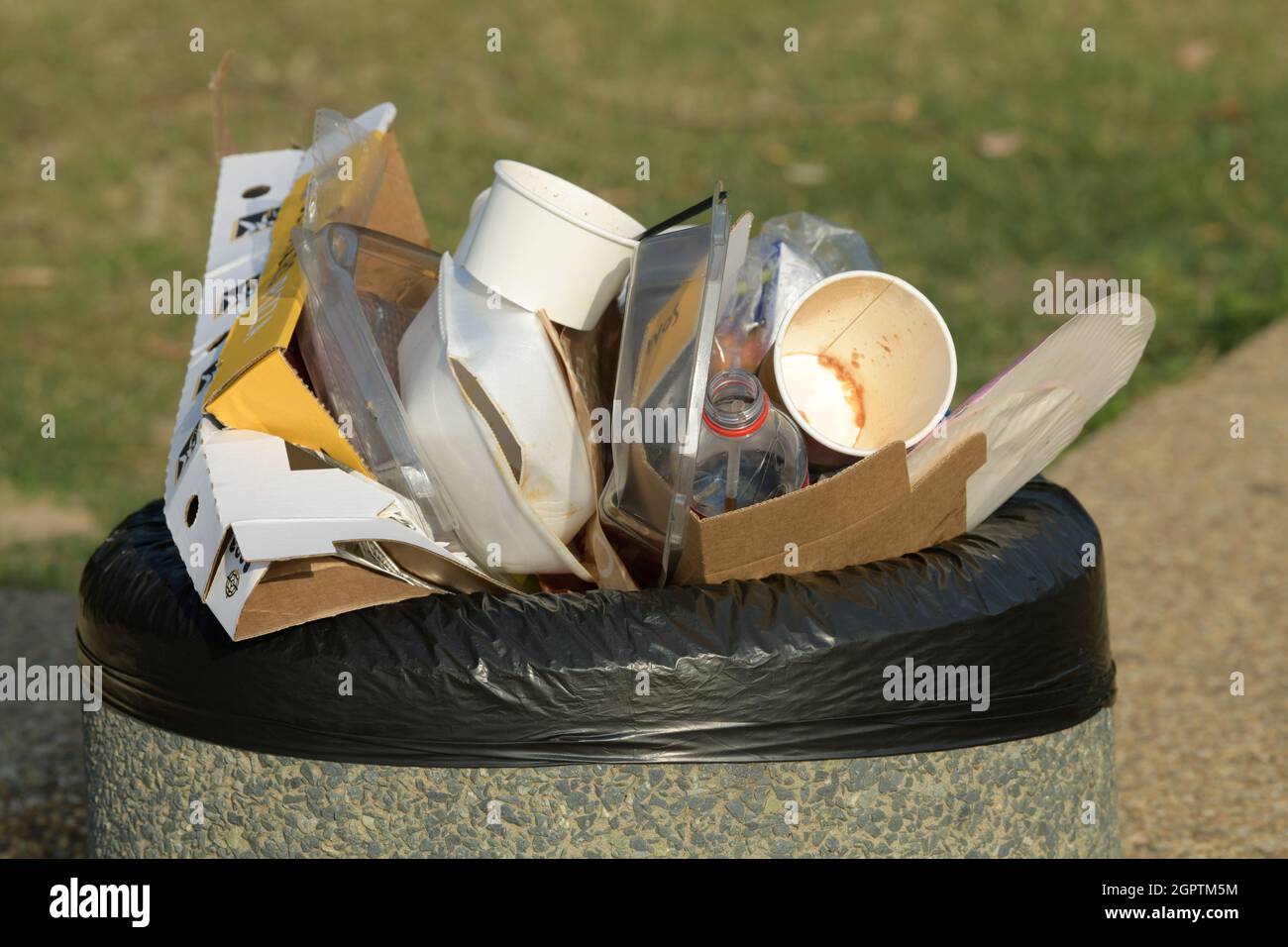 Fast food packaging containers in waste bin, plastic pollution, human