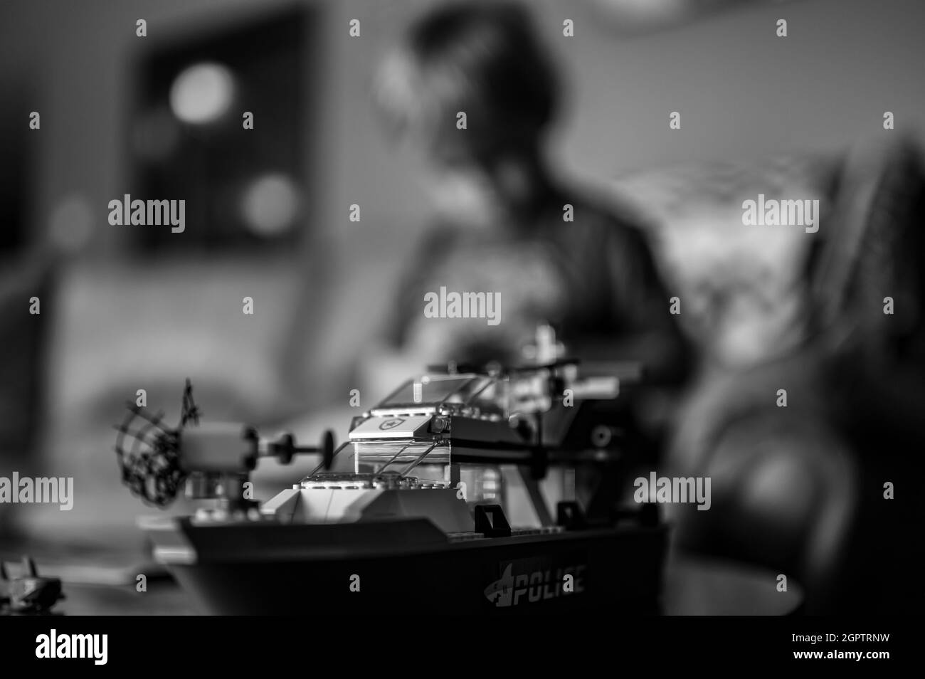 Tiffin, Iowa, USA - 9.2021 - Focus on Lego ship construction set with blurred child in the background playing Stock Photo