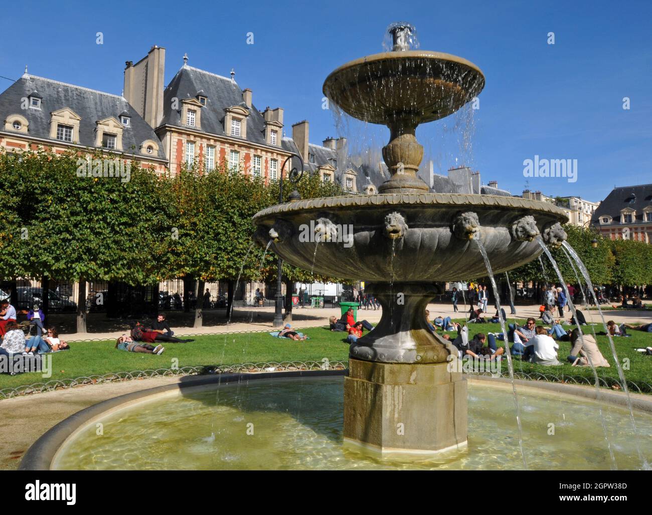 A fountain stands in historic Place des Vosges in the Marais district in Paris. Grand residences line the public square. Stock Photo
