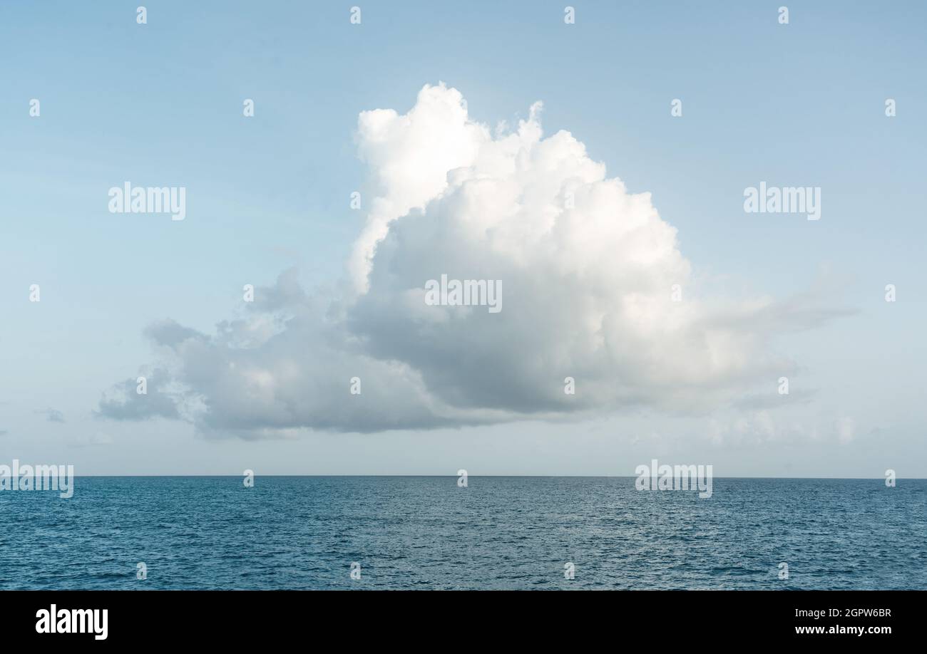 One big white cloud in blue sky over sea landscape. Cloud above ocean ...