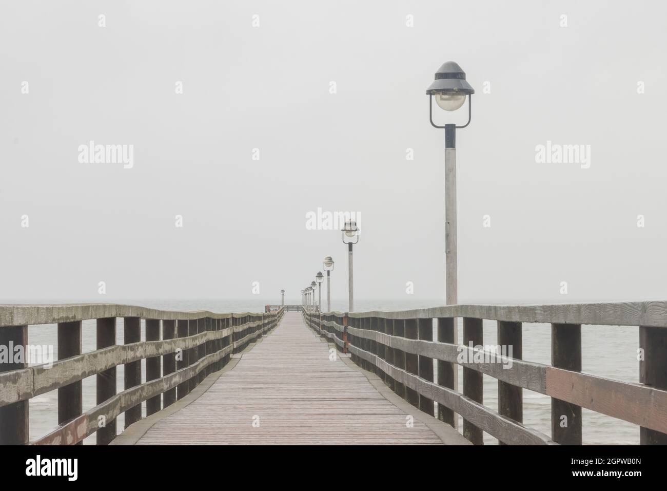 Wooden bridge over the seawater with outdoor lamps on a foggy day Stock ...