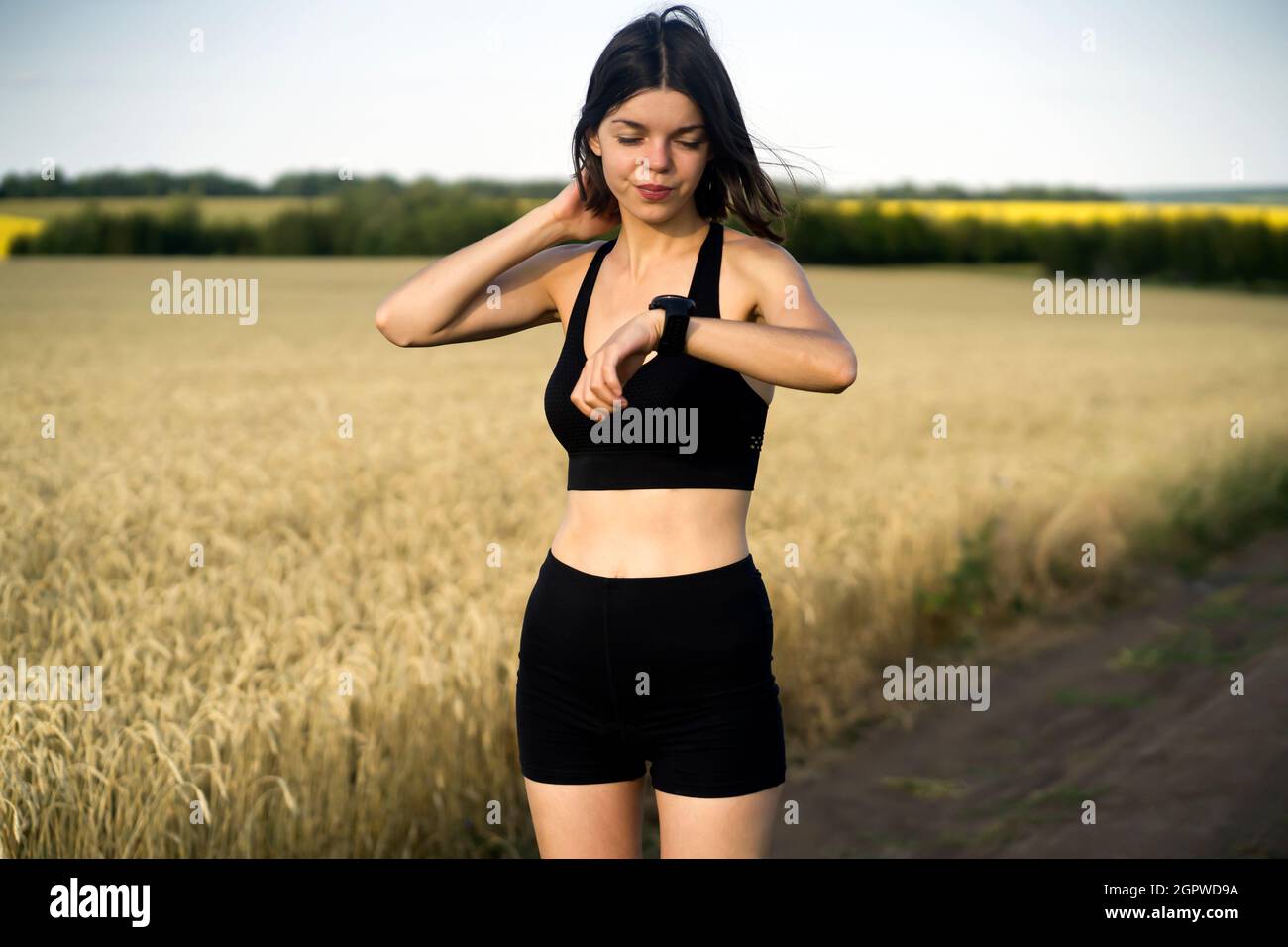 Girl looks at her watch, during running outdoor. Stock Photo