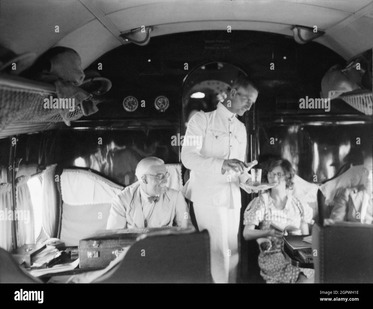 Vintage photo circa 1935 of a steward serving drinks on board an Imperial Airways Handley Page HP 42 airliner over Africa.    The HP 42 were four-engine commercial long-range biplane airliners designed and manufactured by British aviation company Handley Page Stock Photo
