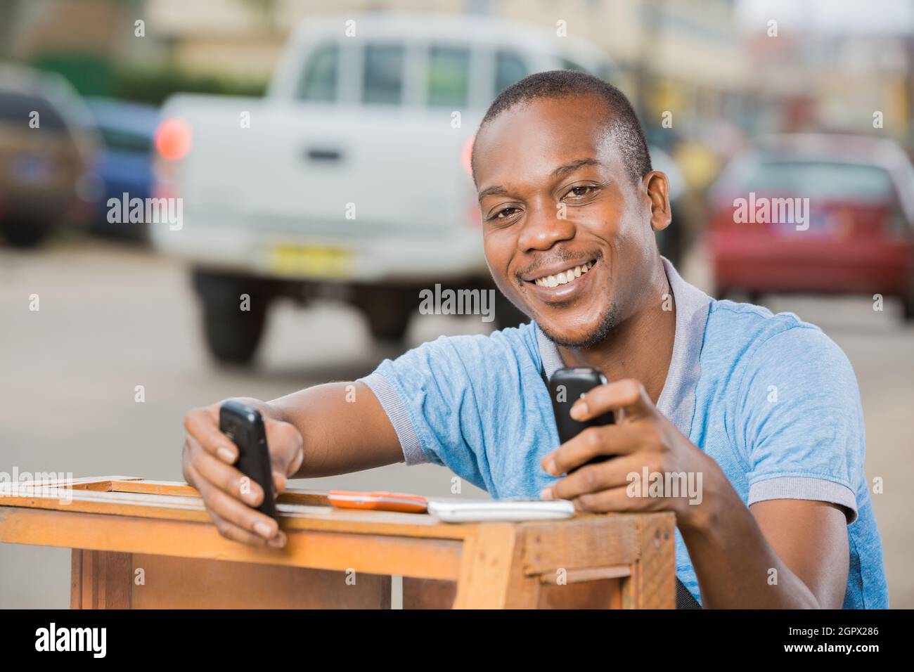 jeune homme assis tenant deux portables noirs Stock Photo