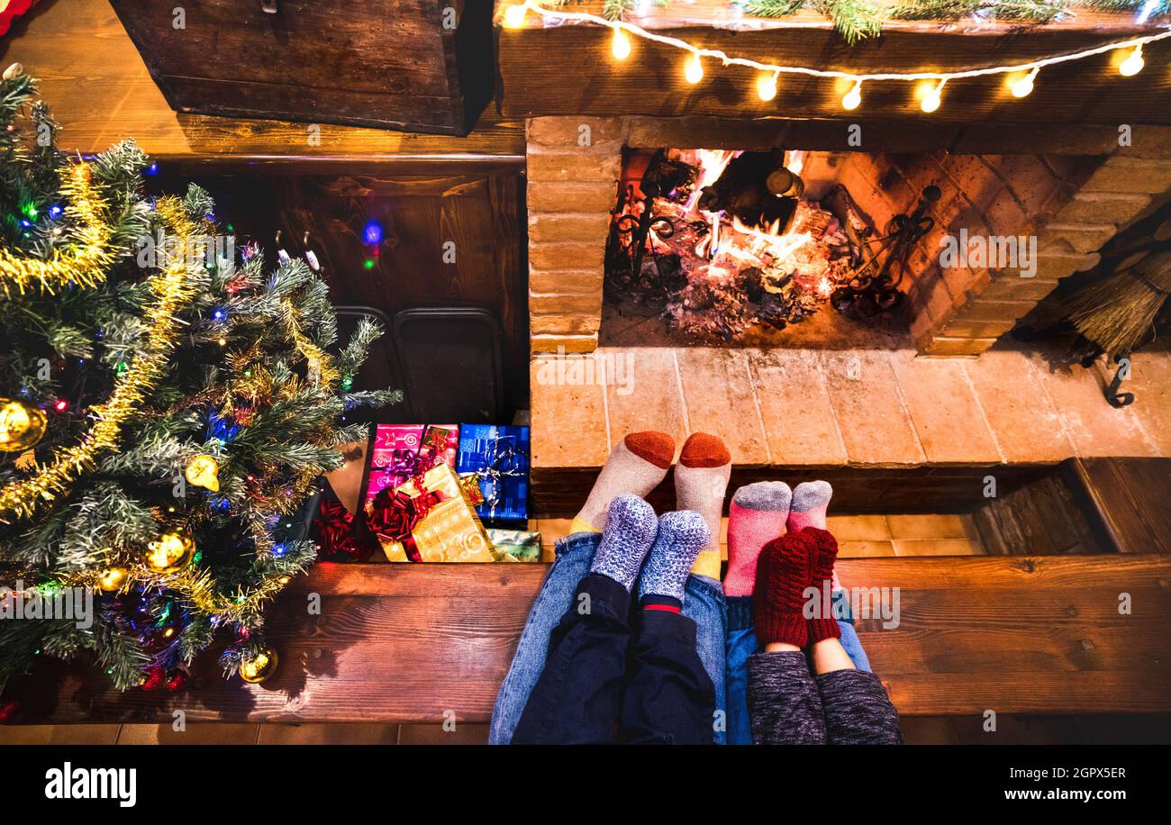 Mother father and kids sitting at cosy fireplace on winter time - Lovely family resting together on woolen socks at home fire place Stock Photo