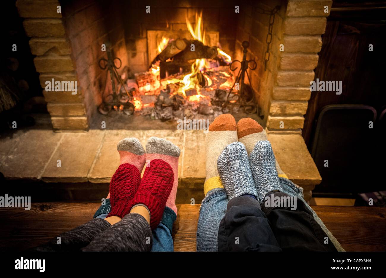 Mother father and kids sitting at cosy fireplace on Christmas time - Lovely family resting together on woolen socks at home fire place Stock Photo
