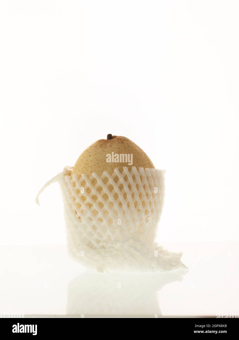 Chinese white pear, Pyrus × bretschneideri, fruit still-life in protective wrapping on plain white background Stock Photo