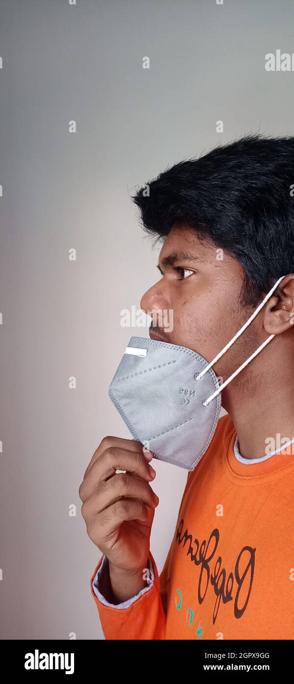 Portrait Of Young Man Holding Mask Against White Background Stock Photo