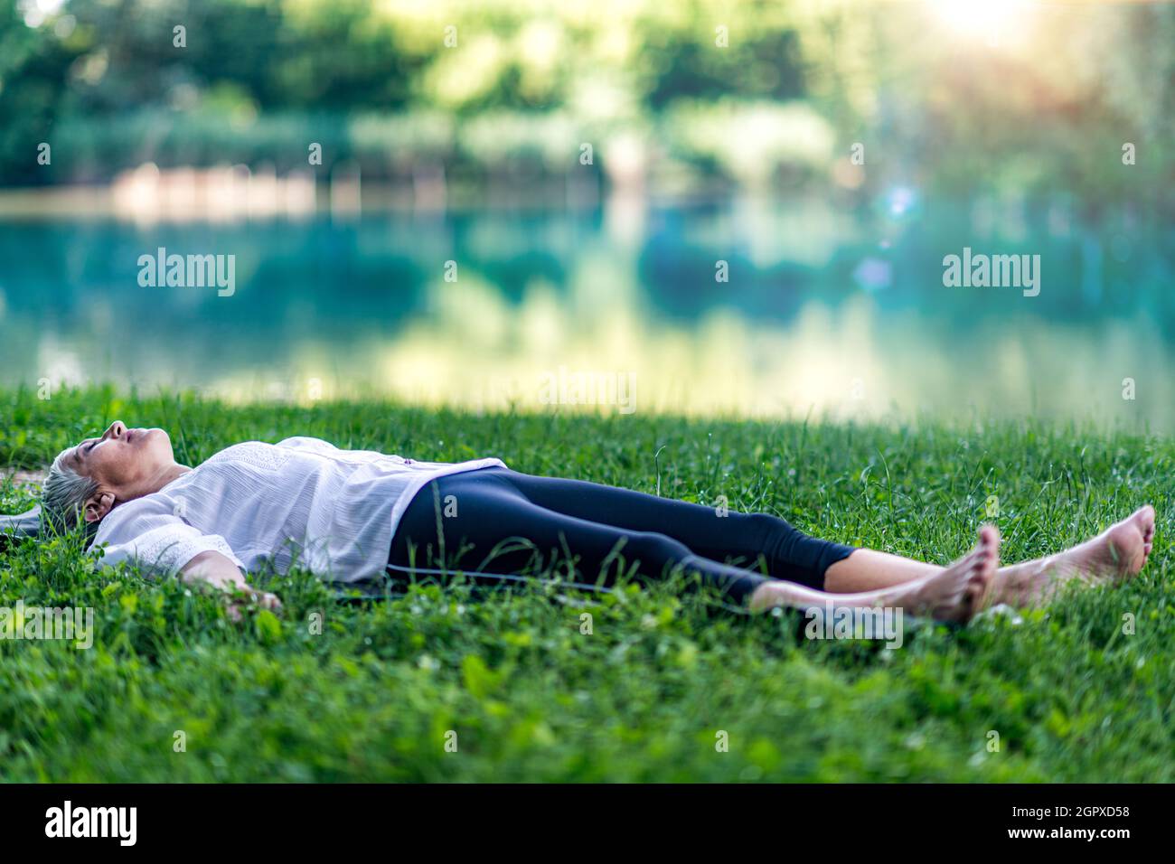 Mindful Mature Woman Meditating By The Water, Lying Down, Feeling