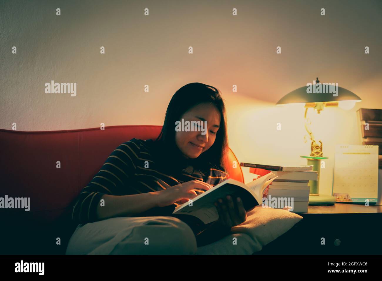 Young Woman Reading Book At Home Stock Photo